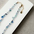 Gemstone necklaces in shades of blue on a white surface