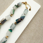 Necklace with green and gray beads on a white card
