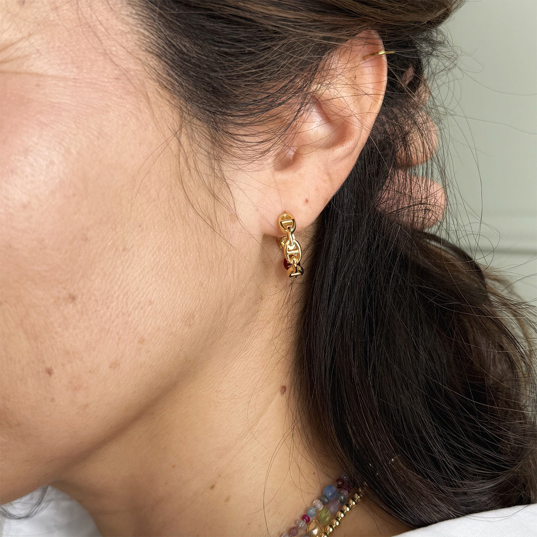 Gold chain link hoop earring worn by a person with dark hair.