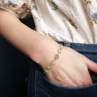 Person wearing a green kyanite bracelet on a dark background