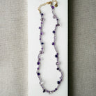 Gemstone necklace in shades of purple on a white surface