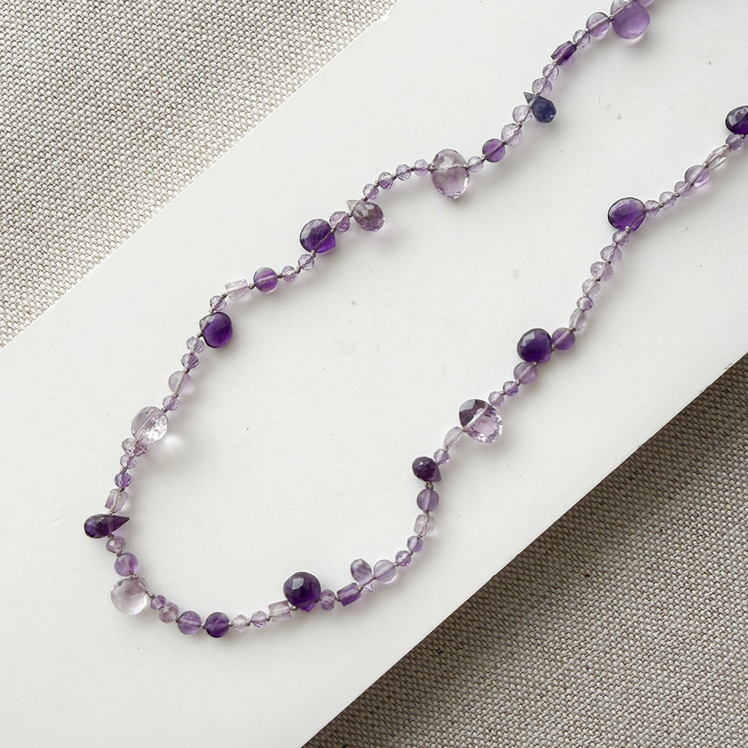 Gemstone necklace in shades of purple on a white surface