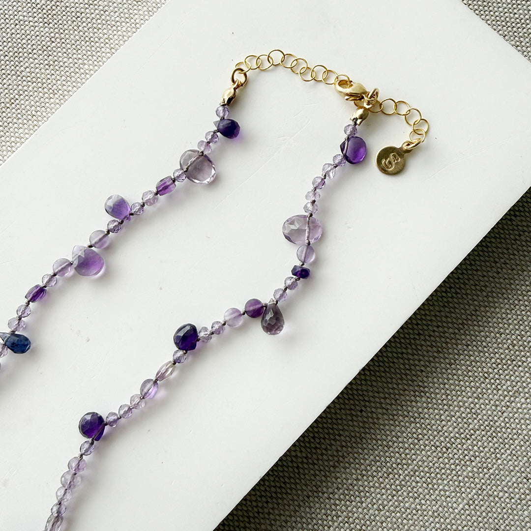 Gemstone necklace in shades of purple on a white surface