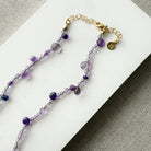 Gemstone necklace in shades of purple on a white surface