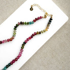 Clasp detail of necklace with smooth Watermelon Tourmaline in shades of pink, red, green, blue, and orange, featuring a small green tourmaline charm