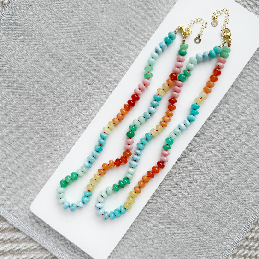 Colorful gemstone beaded necklaces on a white plate with a gray background