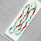 Colorful gemstone beaded necklaces on a white plate with a gray background