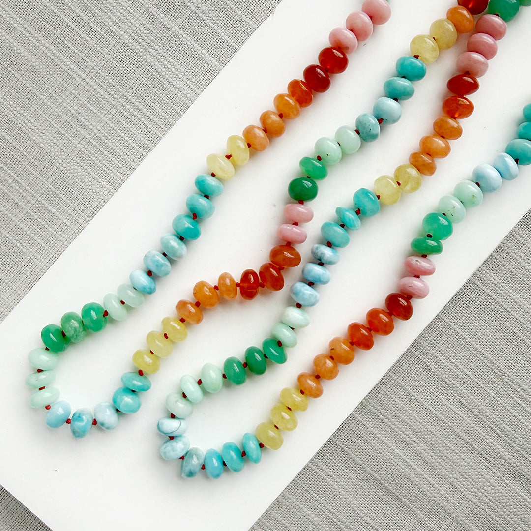 Colorful gemstone beaded necklaces on a white plate with a gray background
