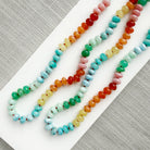 Colorful gemstone beaded necklaces on a white plate with a gray background