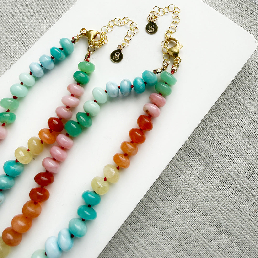 Colorful gemstone beaded necklaces on a white plate with a gray background