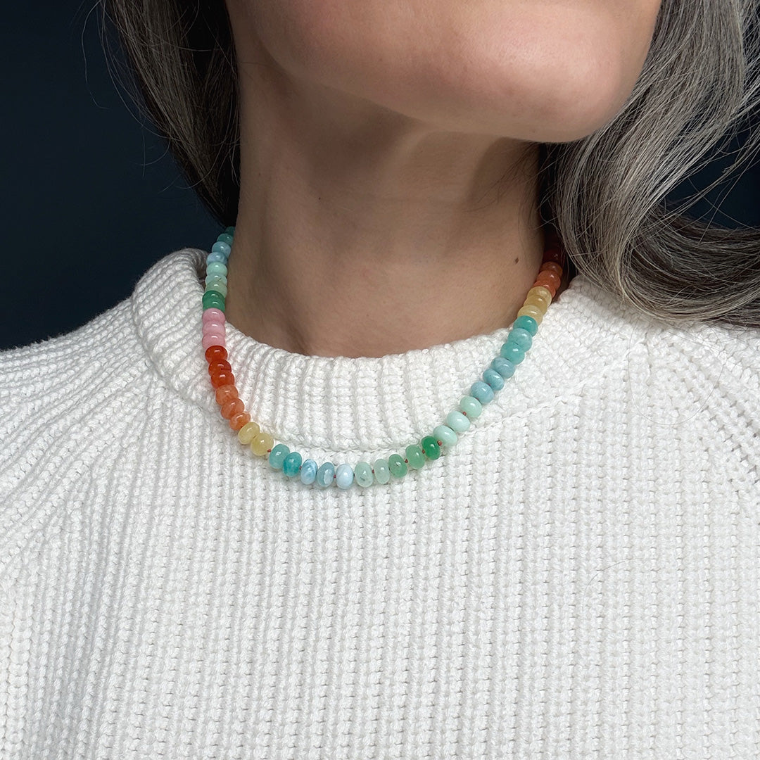 Colorful gemstone beaded necklace worn by a person with a white sweater