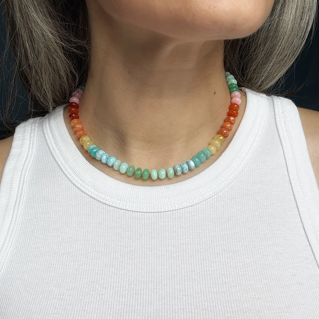 Colorful gemstone beaded necklace worn by a person with a white tank top