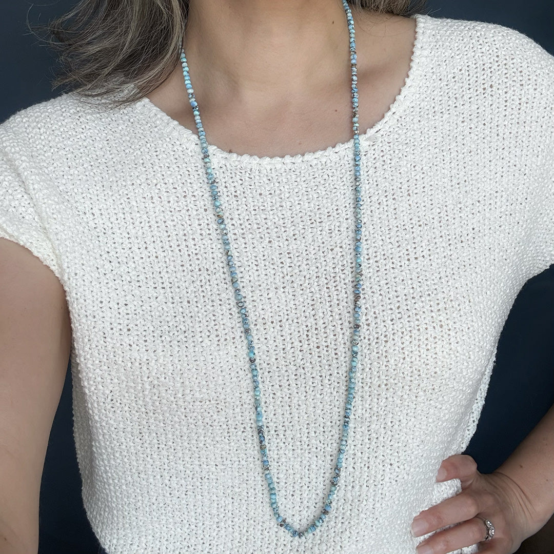 Person wearing a white sleeveless top with a long Golden Hills Turquoise necklace
