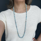 Person wearing a long Golden Hills beaded necklace against a dark background