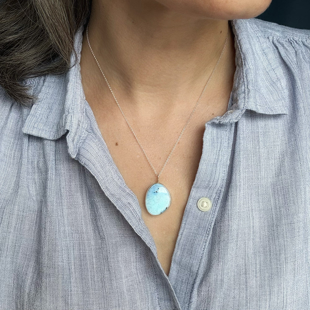 Necklace with a Golden Hills turquoise pendant worn by a person in a light blue shirt.