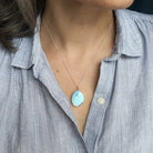 Necklace with a Golden Hills turquoise pendant worn by a person in a light blue shirt.