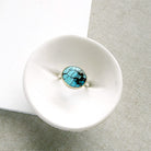 One of a kind Golden Hills turquoise mixed metal ring in a white dish