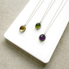 Three gemstone pendants with carved details on a white plate
