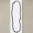 Knotted necklace with smooth sapphire gemstones on a white plate