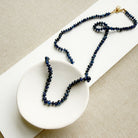 Knotted necklace with smooth sapphire gemstones in a white dish