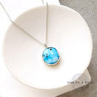 Small Golden Hills pendant set in sterling silver in a white dish