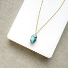 Small oval Golden Hills Pendant set in solid gold on a white plate