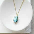 Small oval Golden Hills Pendant set in solid gold in a white dish