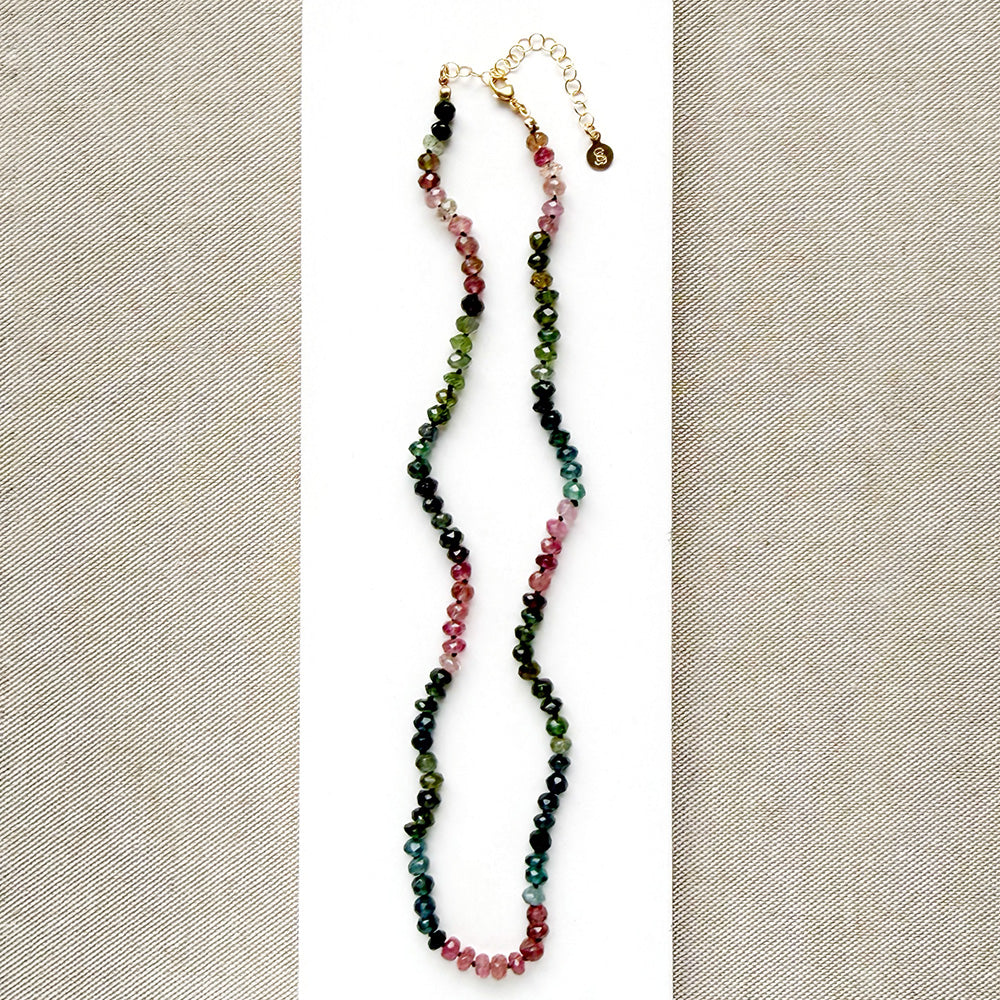 A beaded necklace made of Watermelon Tourmaline faceted round beads in shades of green, blue, and pink, on white card