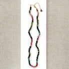A beaded necklace made of Watermelon Tourmaline faceted round beads in shades of green, blue, and pink, on white card