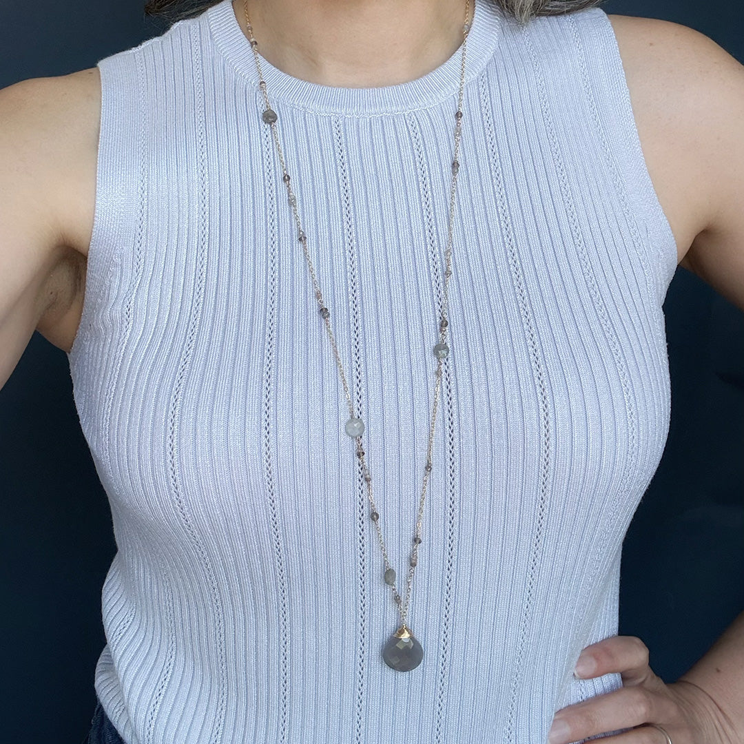 Woman wearing a light blue tank top and a long gemstone necklace