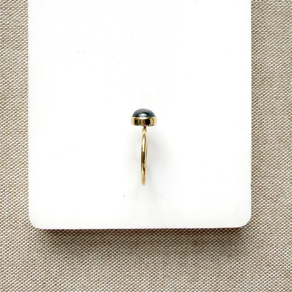 Grey spinel and solid gold ring on a white dish