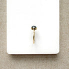Grey spinel and solid gold ring on a white dish