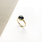Grey spinel and solid gold ring on a white dish