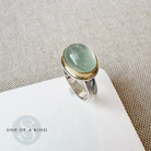 Ring with a green aquamarine stone on a white card with a textured beige background
