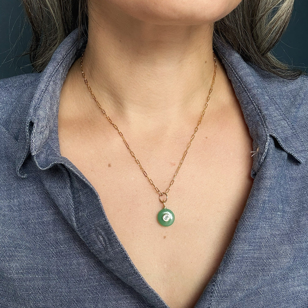 Woman wearing round green chrysoprase charm with inset cz stone