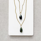Two gold chains with large green tourmaline gemstone charms