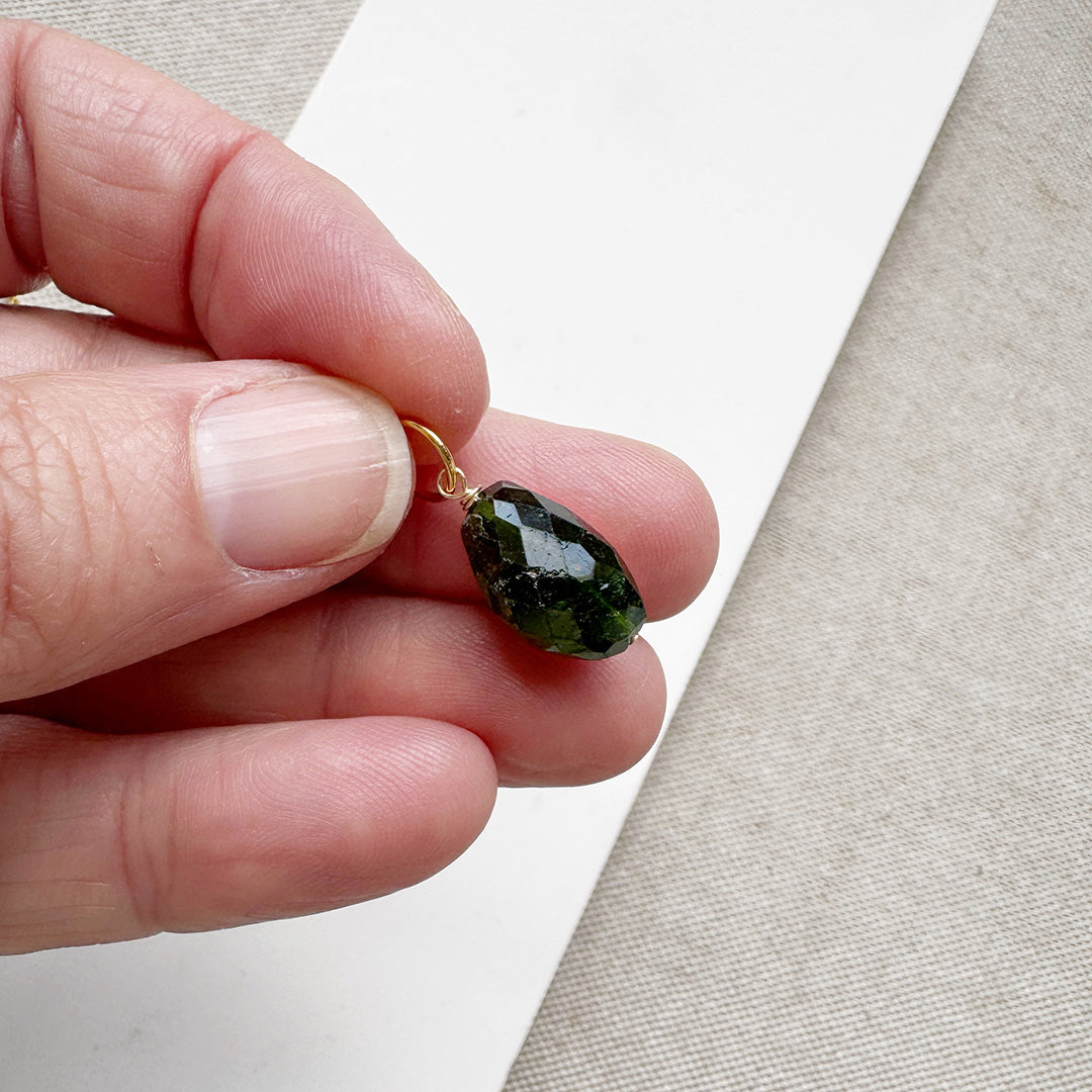 Hand holding a large green tourmaline gemstone charm