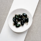 White dish filled with large green tourmaline gemstone charms
