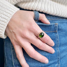 Hand wearing a green tourmaline mixed metal ring
