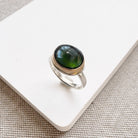 Ring with a green tourmaline gemstone on a white surface