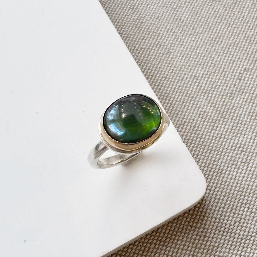 Ring with a green tourmaline gemstone on a white surface