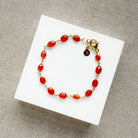 Bracelet with carnelian gemstones on a white card against a textured gray background