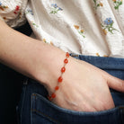 Person wearing a bracelet with carnelian gemstones on a floral shirt and jeans background