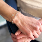 Close-up of a hand wearing a gold bracelet with small gemstones