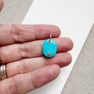 Hand holding an oval blue howlite charm with inset quartz stone