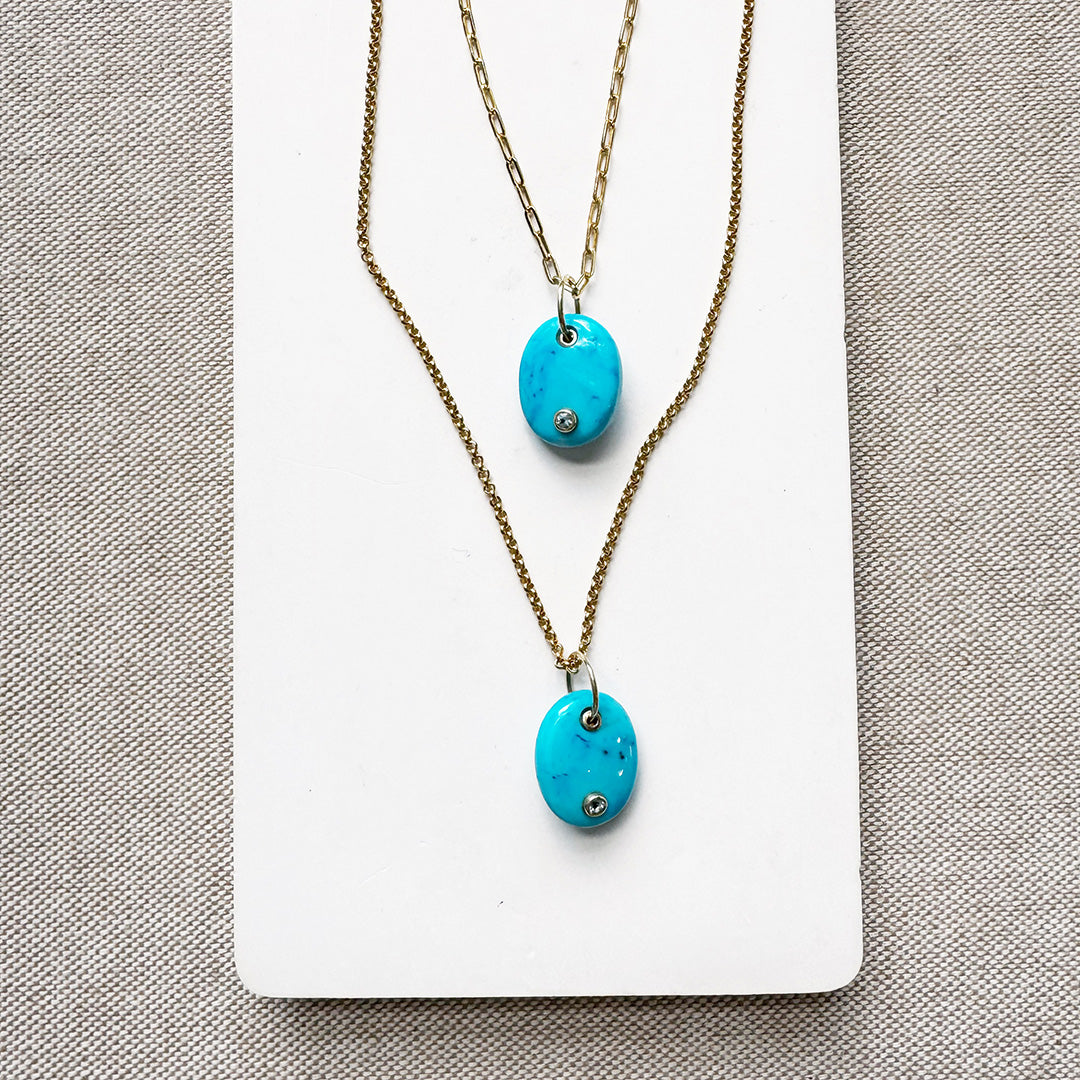 Two gold chains with oval blue howlite charms with inset quartz stones