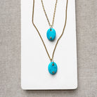 Two gold chains with oval blue howlite charms with inset quartz stones