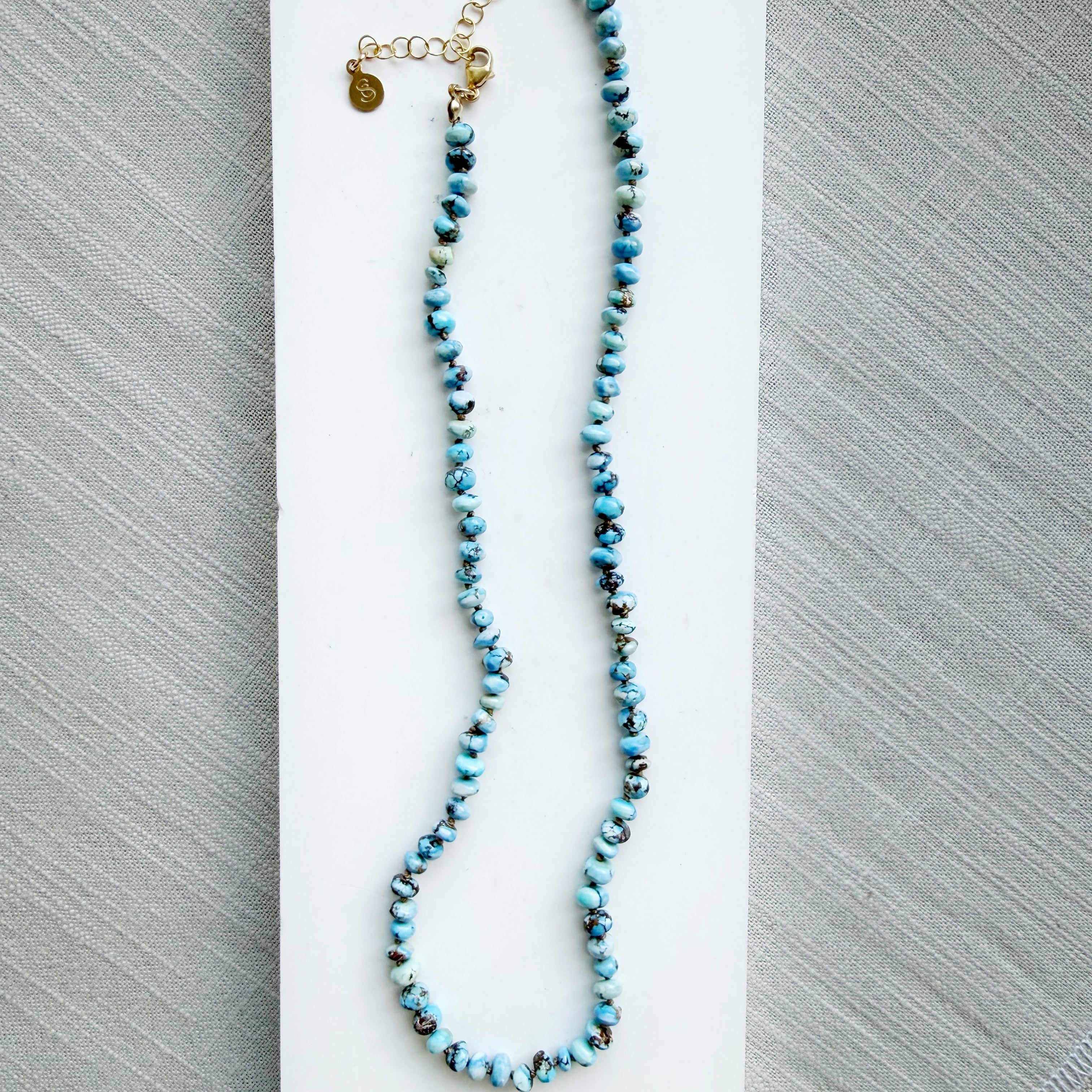 Necklace with Golden Hills turquoise beads on a white dish against a gray background