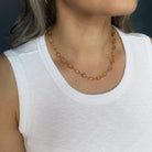 Woman in a white tank wearing an imperial topaz necklace
