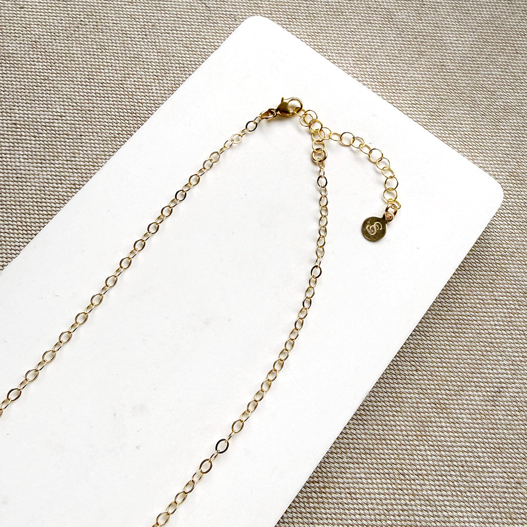 Clasp detail of multicolored gemstone necklace on a white background